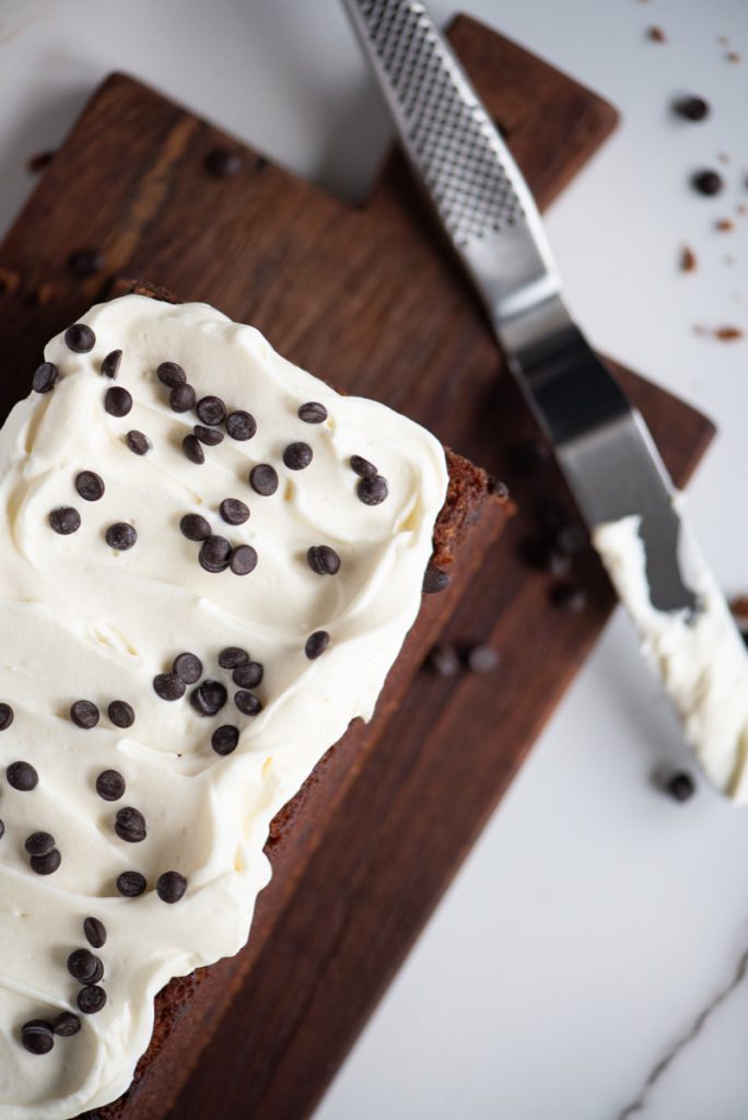 bild ovanifrån på en kaka med vit frosting och chokladknappar. 