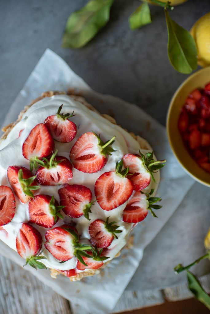 Närbild på jordgubbar ovanifrån  en tårta med grädde. 